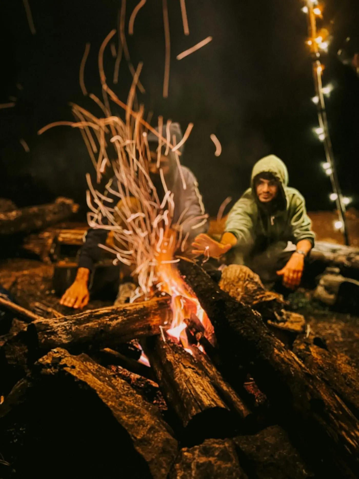 Two friends sitting by a campfire under the night sky