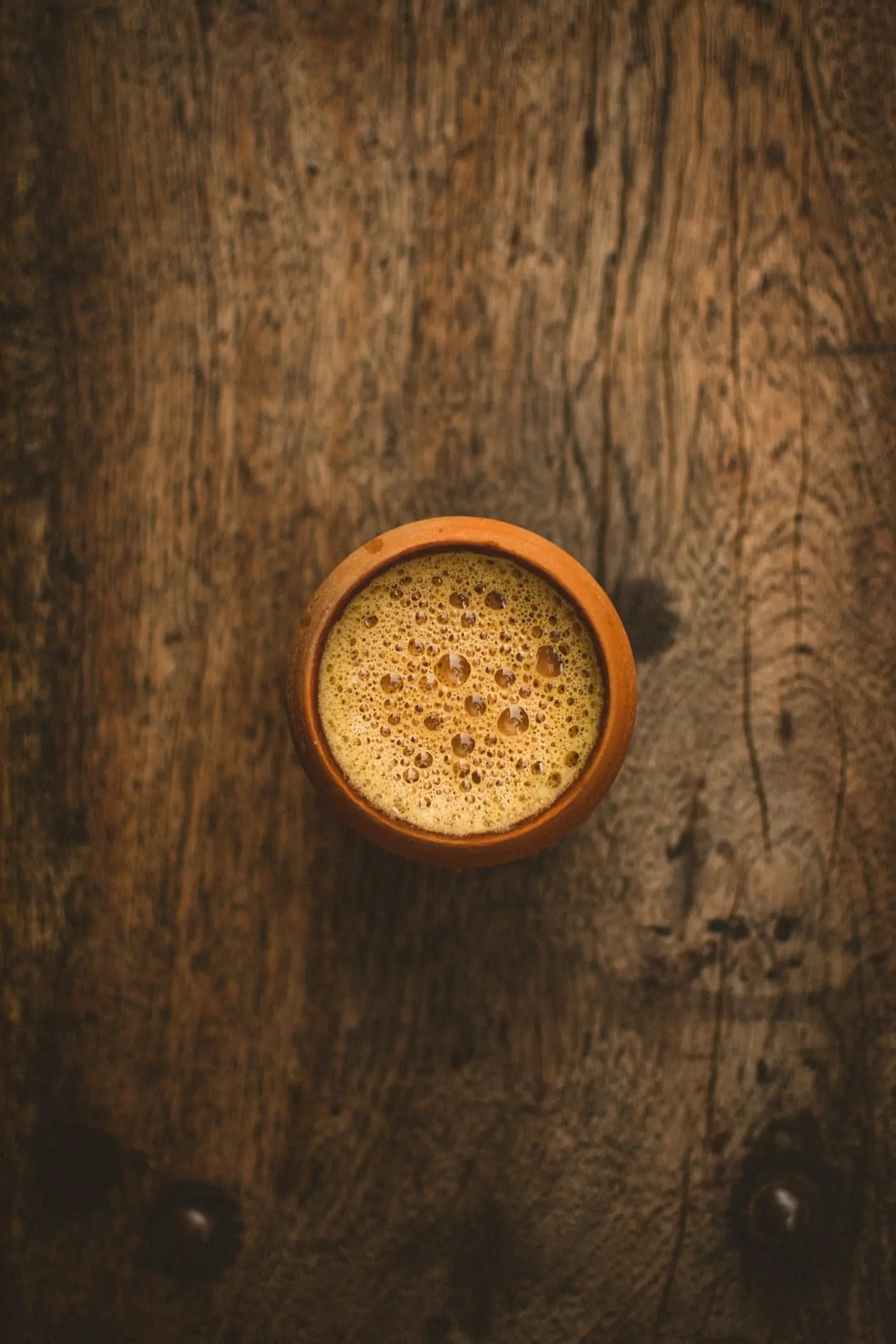 A cup of milky chai on a rustic wooden table