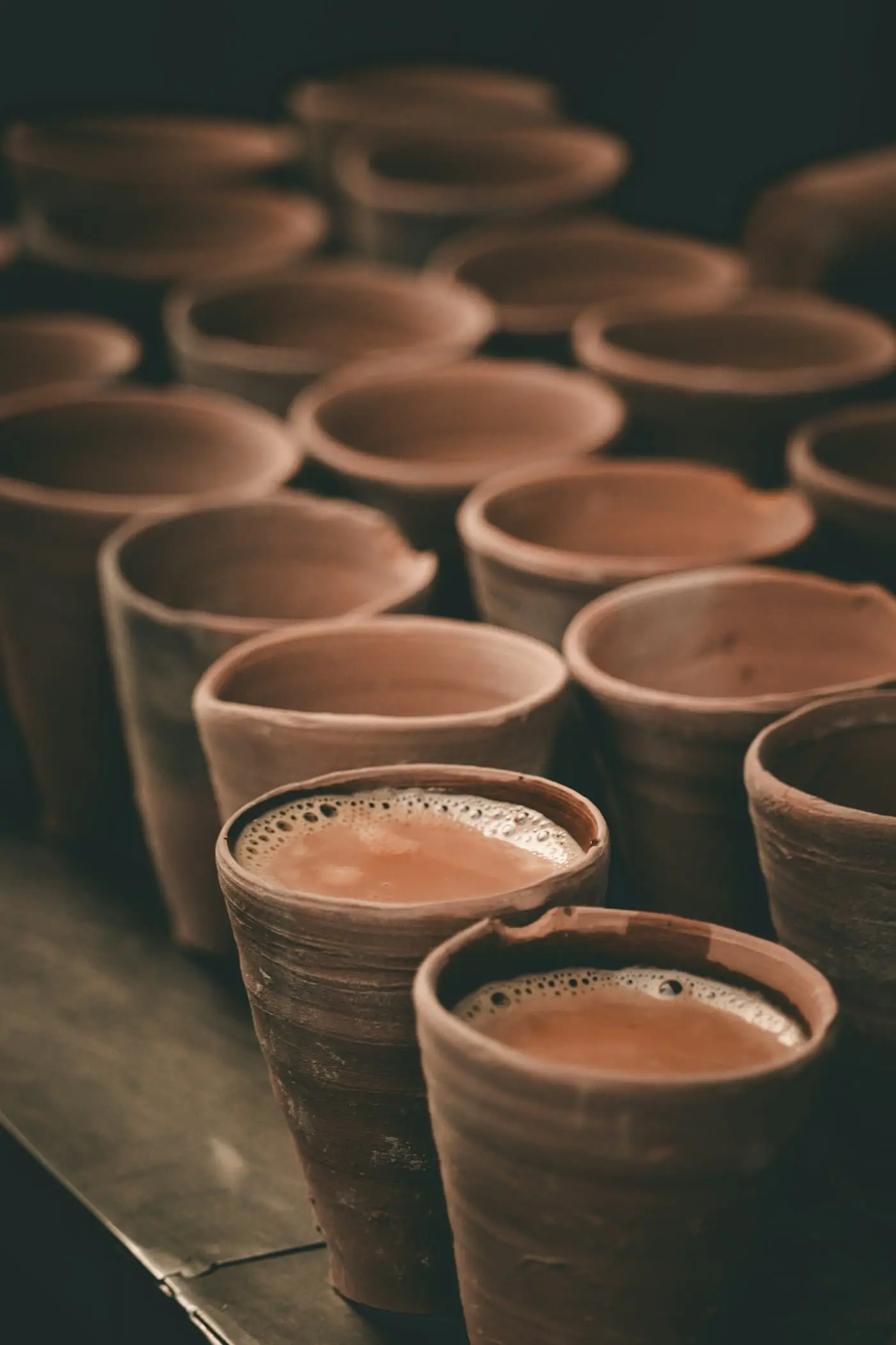 Chai served in clay kulhad cups on a wooden table