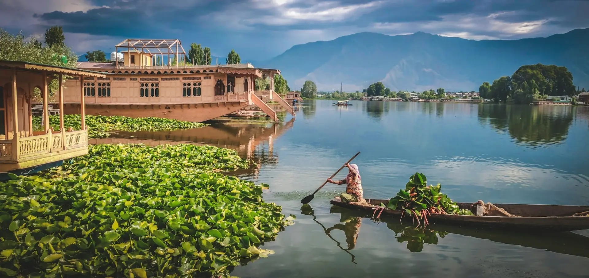 A boatman paddling a shikara across the calm surface of Dal Lake