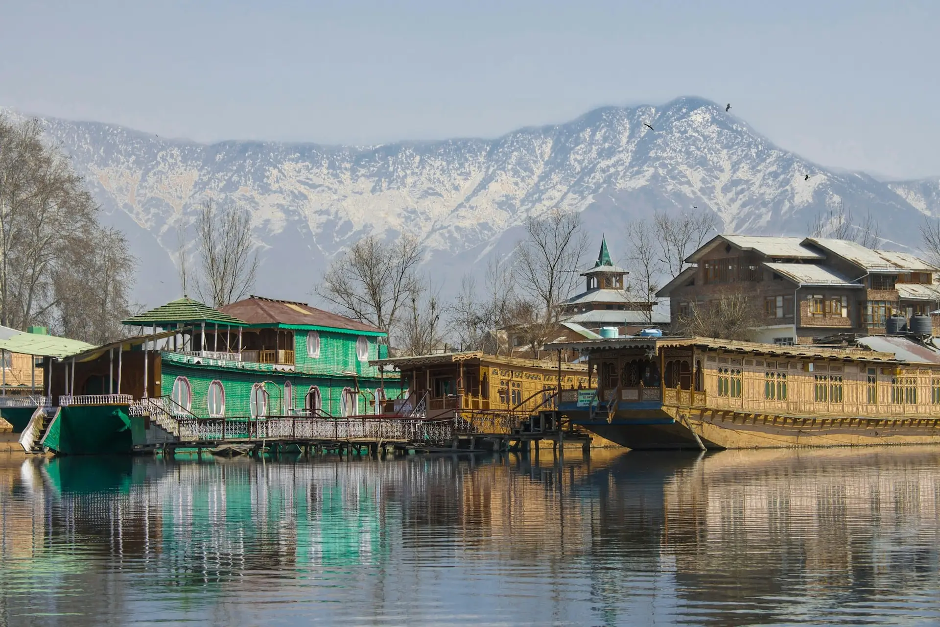 Carved wooden houseboats on Dal Lake with snow on the mountains beyond