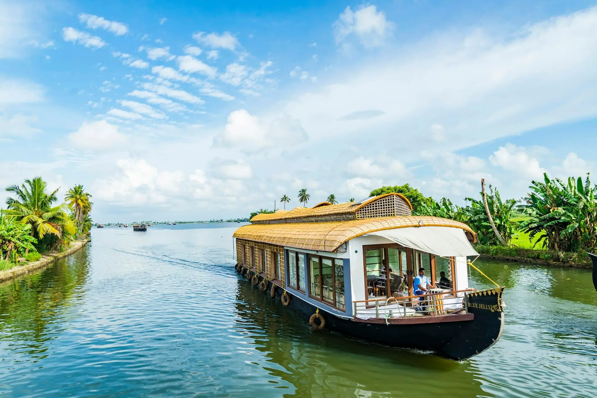A thatched houseboat drifting along a wide backwater in Alappuzha
