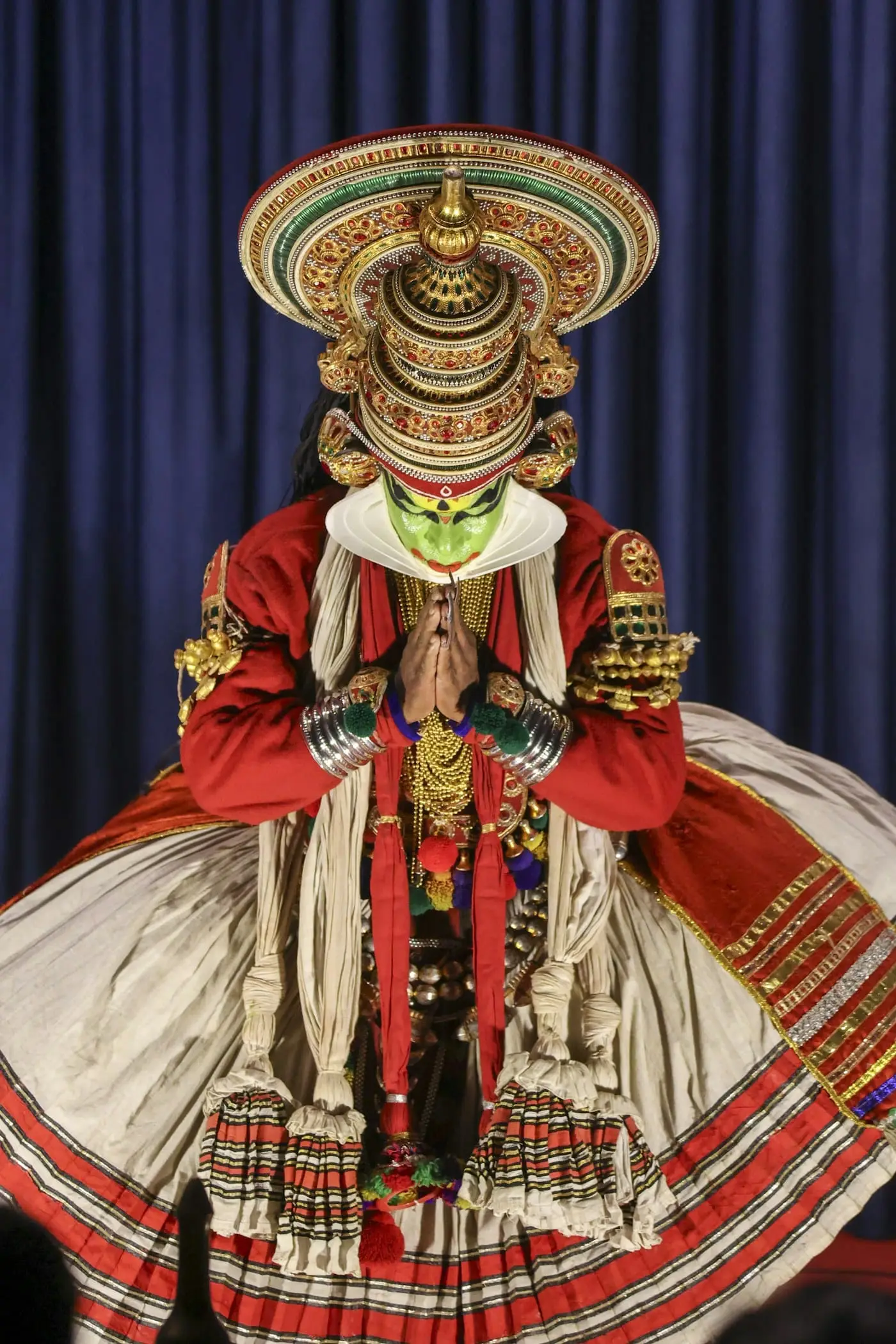 A Kathakali performer in green face paint and an ornate headdress