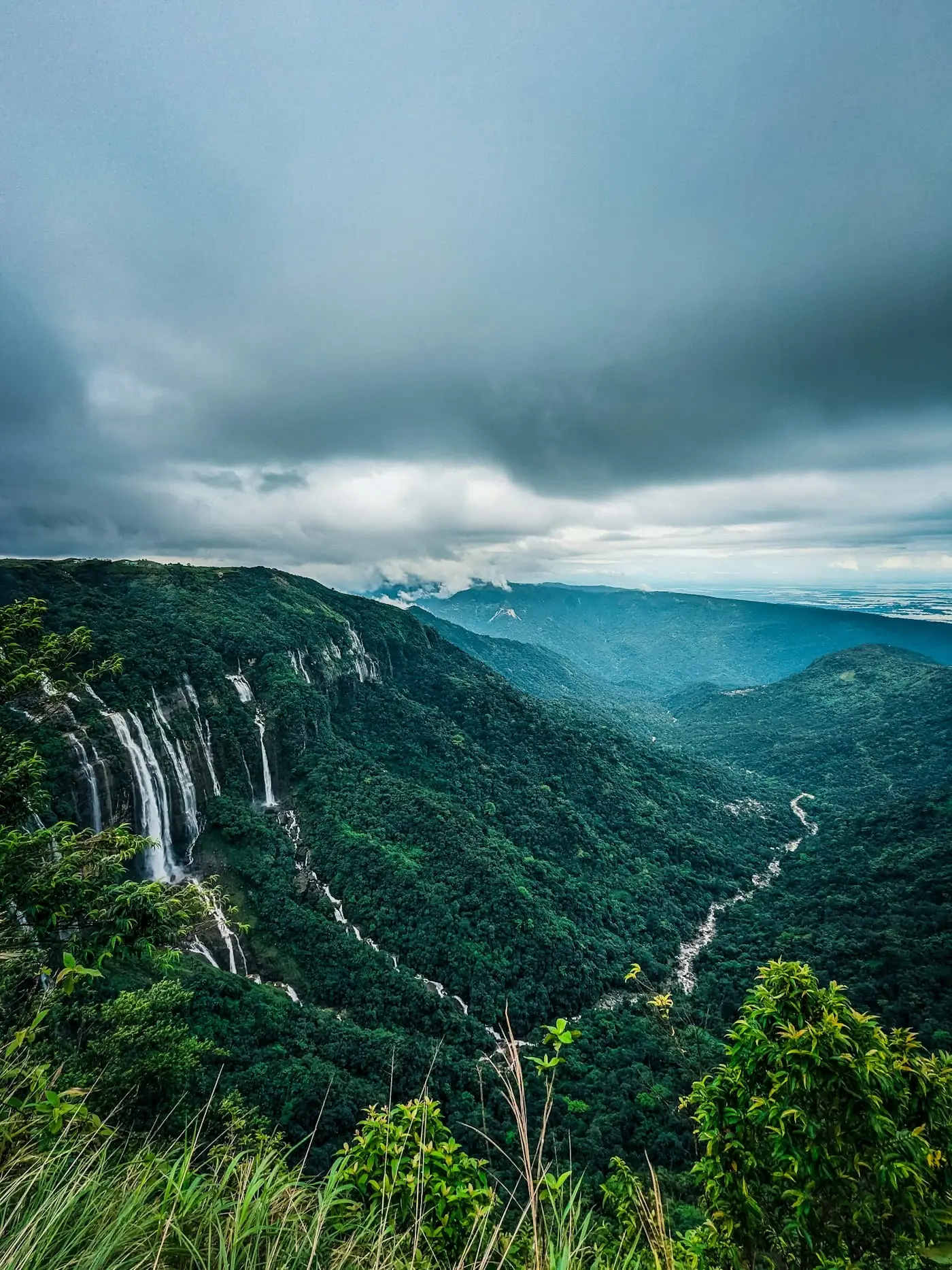 A deep green valley with a distant waterfall near Cherrapunji