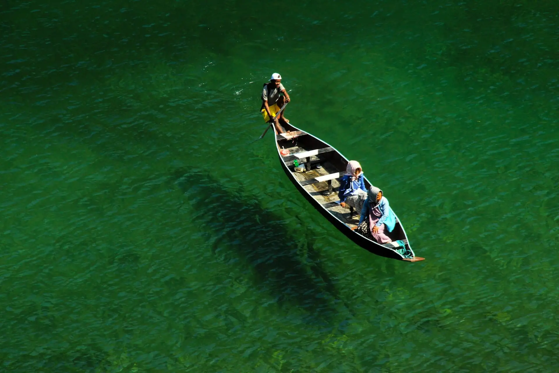 A wooden boat appearing to float on the glass-clear Umngot River at Dawki