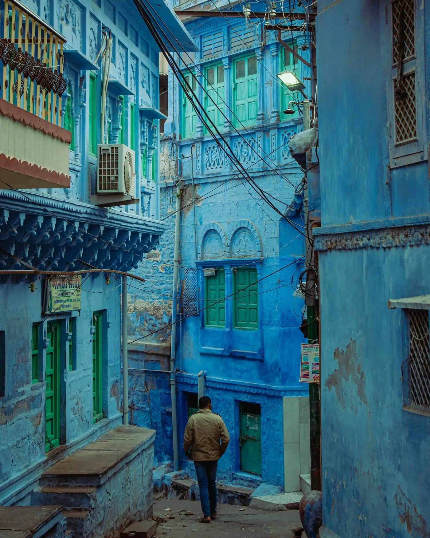 A traveller resting on a bench outside a blue house in Jodhpur