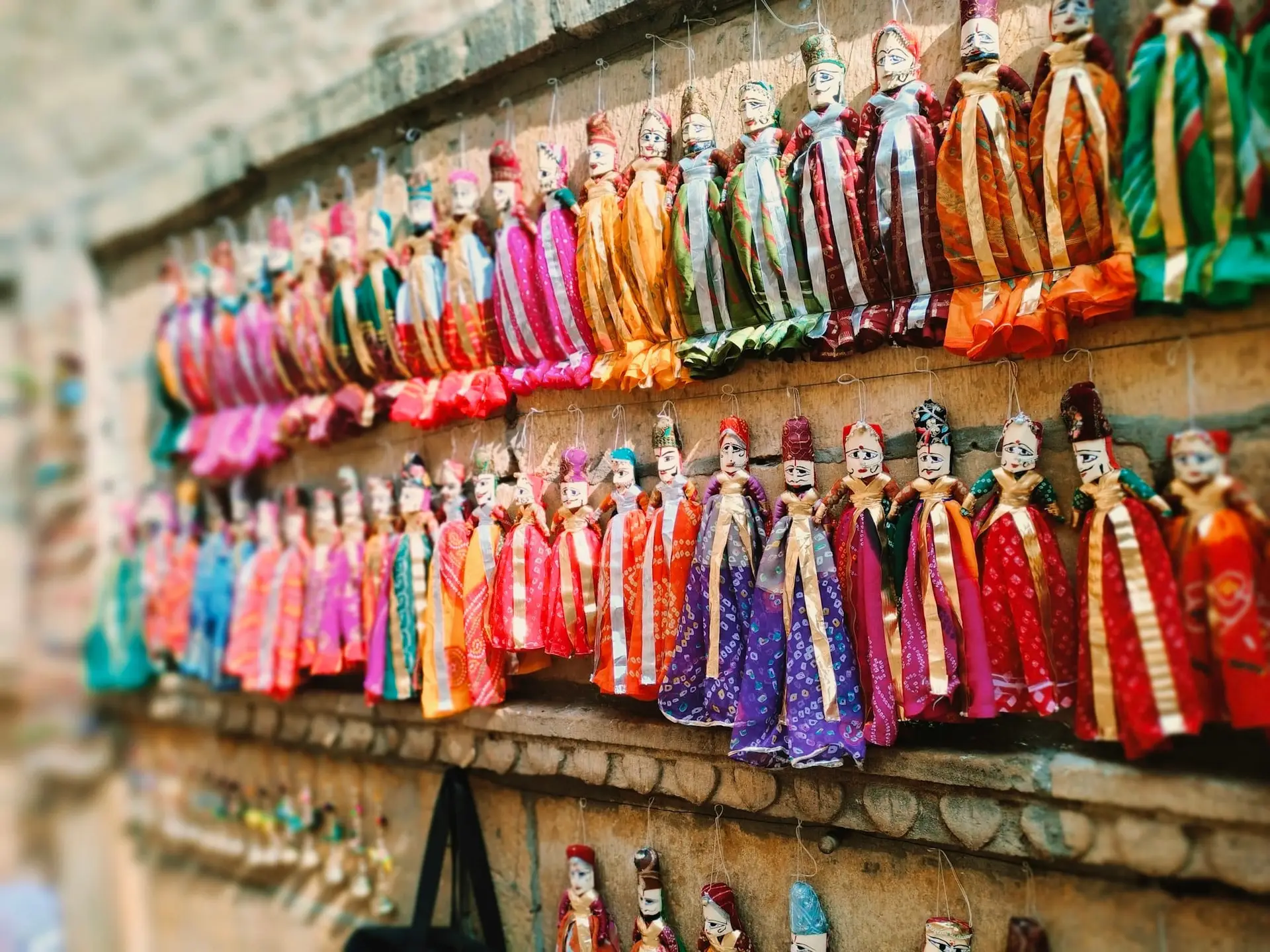Hand-painted Rajasthani kathputli puppets hanging in a Jaisalmer shop